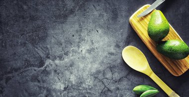 Avokado yemek tarifleri. Tahta kesme tahtasında servis edilen olgun yeşil avokado..