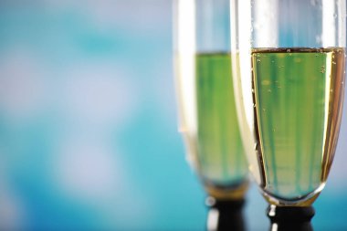 Köpüklü şaraplar için uzun bardaklı bir arka plan. Cam bardaklarda şampanya spreyi. Yansımalı kutlama içkisi.