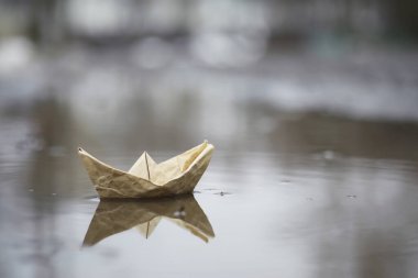 Sokakta kağıttan tekne var. Konsept ilkbaharın başında. Eriyen kar ve su dalgaları üzerinde bir origami teknesi.