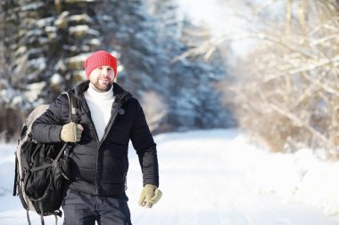 Bir adam sırt çantasıyla seyahat eder. Ormanda kış yürüyüşü. Kışın parkta yürüyüş yapan bir turist..