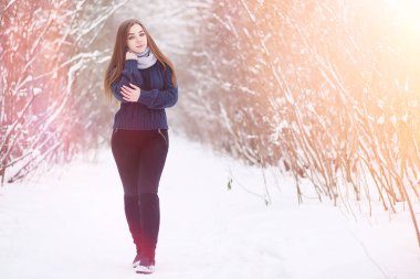 Kış parkında yürüyüş yapan genç bir kız. Kış ormanlarında Noel tatili. Kız parkta kışın tadını çıkarıyor.
