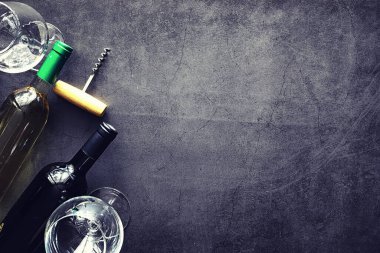 Masada bir bardak kırmızı şarap. Siyah şişe ve bir bardak şarap..