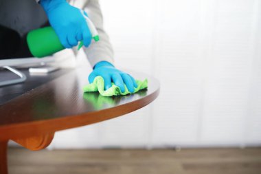 Ev temizliği konsepti. Yüzeylerin tozunu sil. Dezenfektan kapısı TV elektriğini kontrol ediyor. Evdeki karantinada hijyenik tedavi.