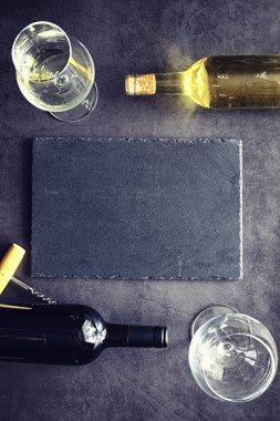 Masada bir bardak kırmızı şarap. Siyah şişe ve bir bardak şarap..