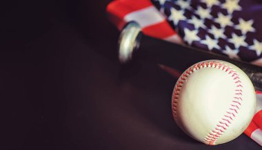 Amerikan geleneksel spor oyunu. Beyzbol mu? Kavram. Amerikan bayrağıyla birlikte beyzbol topu ve sopalar masada..