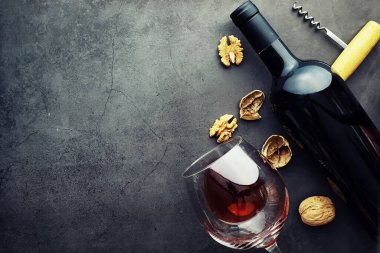 Taş zeminde kırmızı şarap. Şarap kadehi ve siyah şarap şişesi. Fındık peynir ve domates snack için.