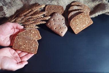Siyah bir masada buğday ve glüten ile taze somun ekmek. Fırın ve market konsepti. Taze, sağlıklı çavdar ve beyaz somun ekmeği, çuval bezi üzerine serpiştirilmiş un. Tahıllı taze ev yapımı ekmek..