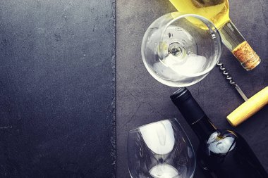 Masada bir bardak kırmızı şarap. Siyah şişe ve bir bardak şarap..