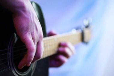 Sahnede telli bir enstrüman çalan sanatçı için akustik gitar. Capo 'lu siyah gitar. Müzik arkaplanı.