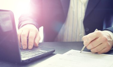 Müdür ofisteki bir dizüstü bilgisayarda çalışıyor. İşadamı çevrimiçi işlem yapıyor. Değiş tokuş internet üzerinden yapılıyor..