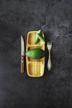Avokado yemek tarifleri. Tahta kesme tahtasında servis edilen olgun yeşil avokado..