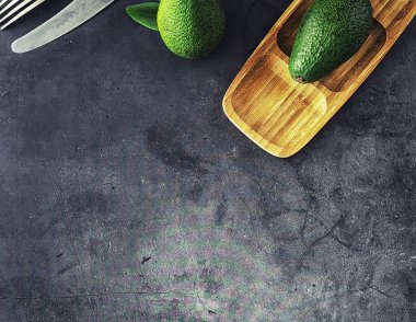 Avokado yemek tarifleri. Tahta kesme tahtasında servis edilen olgun yeşil avokado..