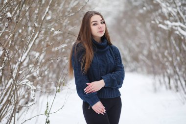 Kış parkında yürüyüş yapan genç bir kız. Kış ormanlarında Noel tatili. Kız parkta kışın tadını çıkarıyor.