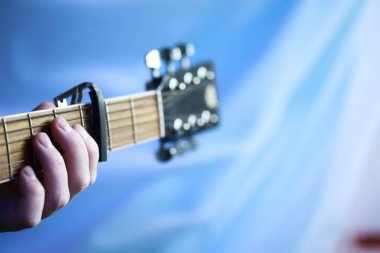 Sahnede telli bir enstrüman çalan sanatçı için akustik gitar. Capo 'lu siyah gitar. Müzik arkaplanı.