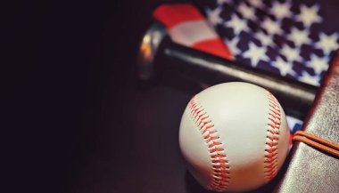 Amerikan geleneksel spor oyunu. Beyzbol mu? Kavram. Amerikan bayrağıyla birlikte beyzbol topu ve sopalar masada..