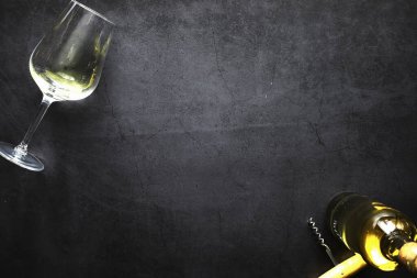 Masada bir bardak kırmızı şarap. Siyah şişe ve bir bardak şarap..