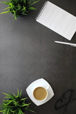 Ofis masaüstü arka planında bir fincan kahve ve yazma aletleri var. Müdürün masası, kalemi, defteri..