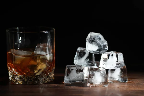 木製のカウンターで氷と強いアルコール飲料のガラス 氷のキューブとウィスキー 冷たい飲み物とガラス — ストック写真