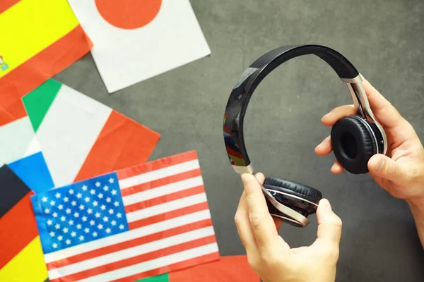 Learning foreign languages. Audio language courses. Background from countries flags and headphones on table.