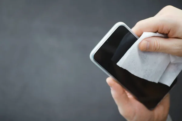 Cleaning concept. Wipe dirt off surfaces. Disinfectant treatment of phone screenl. Sanitary treatment at home in quarantine.