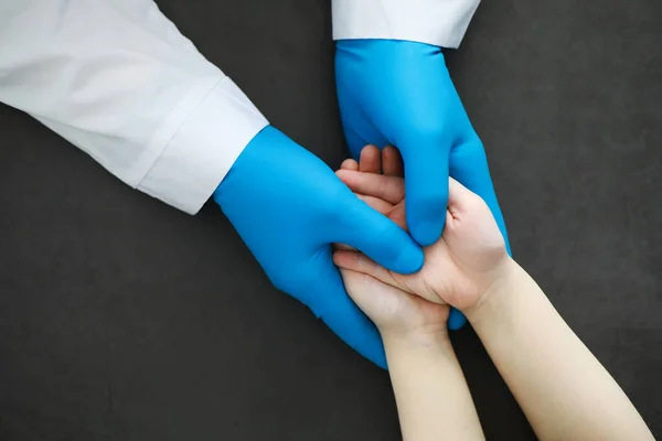Medical concept. The doctor in gloves holds patient's hand. The moral help of the doctor to his patients. Cardiologist consultation. Epidemic.
