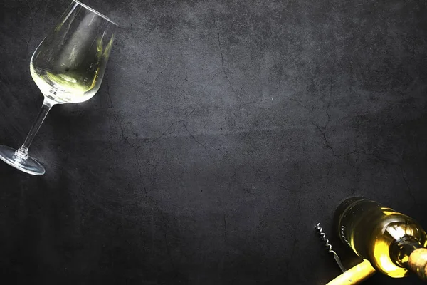 Masada bir bardak kırmızı şarap. Siyah şişe ve bir bardak şarap..