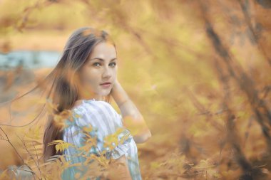 Genç kız sonbahar parkında yürüyüş yapıyor.