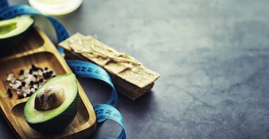 Avokado yemek tarifleri. Tahta kesme tahtasında servis edilen olgun yeşil avokado..