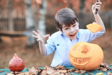 Sonbahar gelenekleri ve Cadılar Bayramı hazırlıkları. Doğada bir ev, masada balkabağından yapılmış bir lamba kesilir..