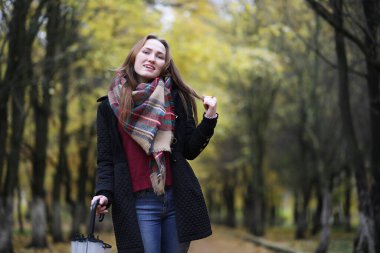 Sonbahar parkında şemsiyesi olan genç bir kız. 