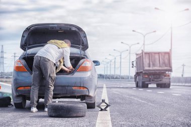 Yoldaki bir arabanın tekerleğini değiştirmek. Kenarda lastik işi yapan bir adam..