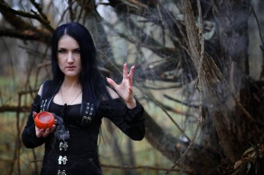 Bir kadın bir ritüel üzerinde yoğun bir orman içinde bir cadı elbiseli
