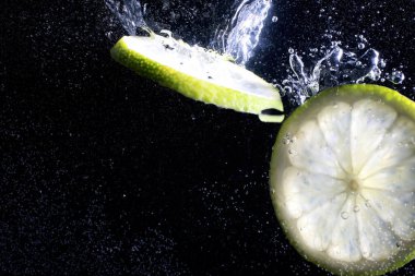 Olgun tatlı limonun üzerine su damlıyor. Metnin için kopyalama alanı olan taze kireç arkaplanı. Vejetaryen ve vejetaryen kavramı.