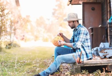 Sonbahar gelenekleri ve Cadılar Bayramı hazırlıkları. Doğada bir ev, masada balkabağından yapılmış bir lamba kesilir..