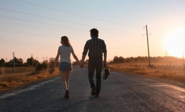 Bir çift genç adam ve bir kız sonbahar çayırında yürüyorlar.