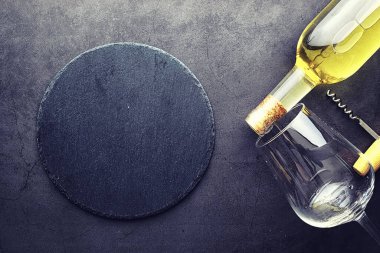 Masada bir bardak kırmızı şarap. Siyah şişe ve bir bardak şarap..