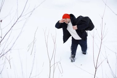 Kışın ormanda bir adam. Sırt çantalı bir turist kışın ormana gider..