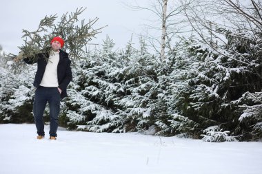 Karla kaplı sokakta Noel ağacı kesen bir adam. Yeni yıl için hazırlık.