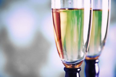 Köpüklü şaraplar için uzun bardaklı bir arka plan. Cam bardaklarda şampanya spreyi. Yansımalı kutlama içkisi.