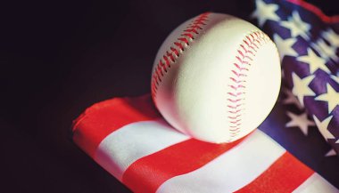 Amerikan geleneksel spor oyunu. Beyzbol mu? Kavram. Amerikan bayrağıyla birlikte beyzbol topu ve sopalar masada..
