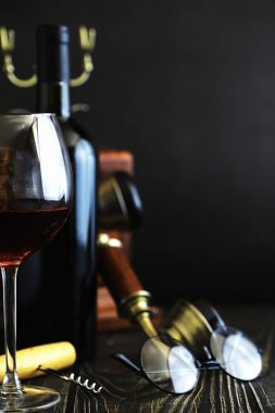 Masada bir bardak kırmızı şarap. Siyah şişe ve bir bardak şarap..