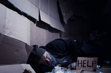 Evsiz sakallı bir adam sokakta kutulara oturup yardım istiyor. Evsiz bir insan yemek için para ister ve bir gecede.