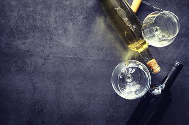 Masada bir bardak kırmızı şarap. Siyah şişe ve bir bardak şarap..