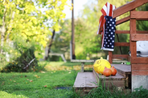 Autumn traditions and preparations for the holiday Halloween. A house in nature, a lamp made of pumpkins is cut out at the table.