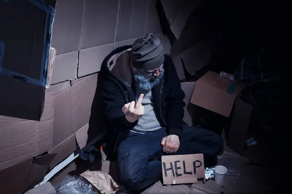 ホームレスの髭を生やした男が通りの箱の上に座って助けを求める ホームレスの人が食料と一夜のためにお金を要求する必要がある — ストック写真
