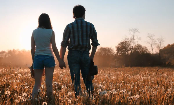 2人の若い男と女の子が秋の草原を歩いています — ストック写真