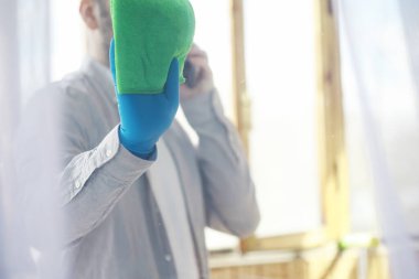 Ev temizliği konsepti. Yüzeylerin tozunu sil. Dezenfektan kapısı TV elektriğini kontrol ediyor. Evdeki karantinada hijyenik tedavi.