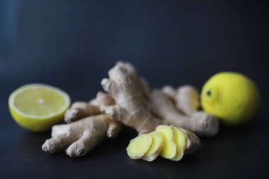 Zencefil kökü bütün ve dilimlenmiş. Koyu arkaplanda limonlu zencefil çayı. Taş zeminde taze zencefil kökü. Vitaminler. Üst Manzara. Metnin için boş yer.