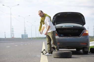 Yoldaki bir arabanın tekerleğini değiştirmek. Kenarda lastik işi yapan bir adam..