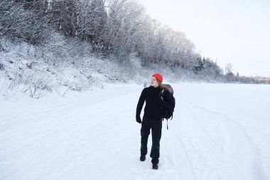 Bir adam sırt çantasıyla seyahat eder. Ormanda kış yürüyüşü. Kışın parkta yürüyüş yapan bir turist..
